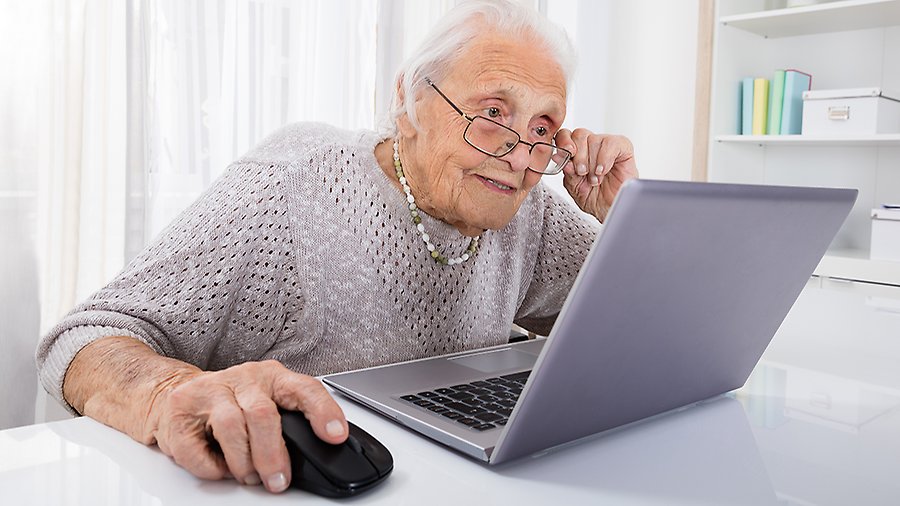 En äldre kvinna sitter vid en laptopdator. 
